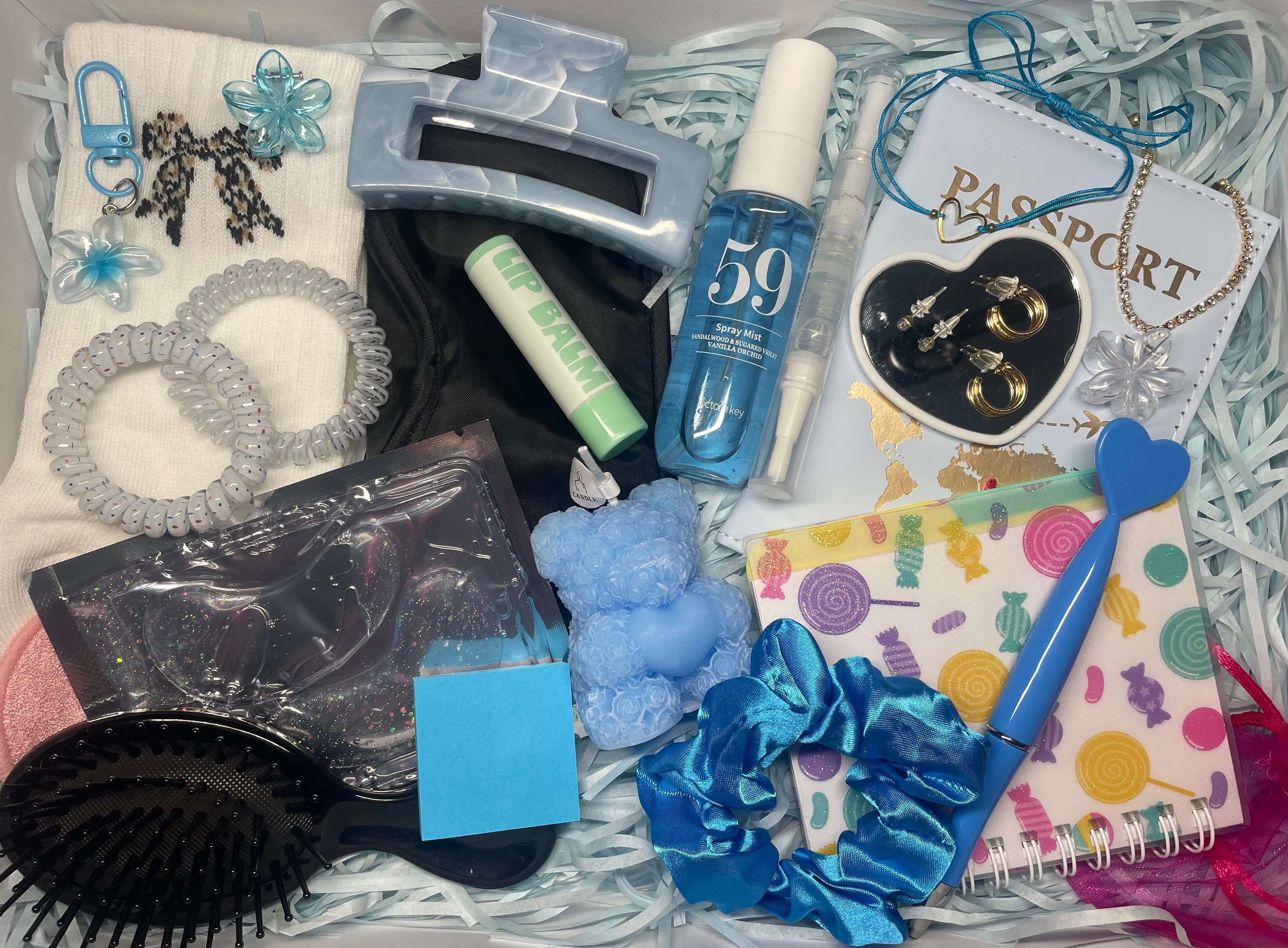 Coffret cadeau sur le thème bleu, contenant de nombreux accessoires : porte passeport, pince à cheveux, brosse, baume à lèvres, carnet, bijoux et beaucoup d'autres.