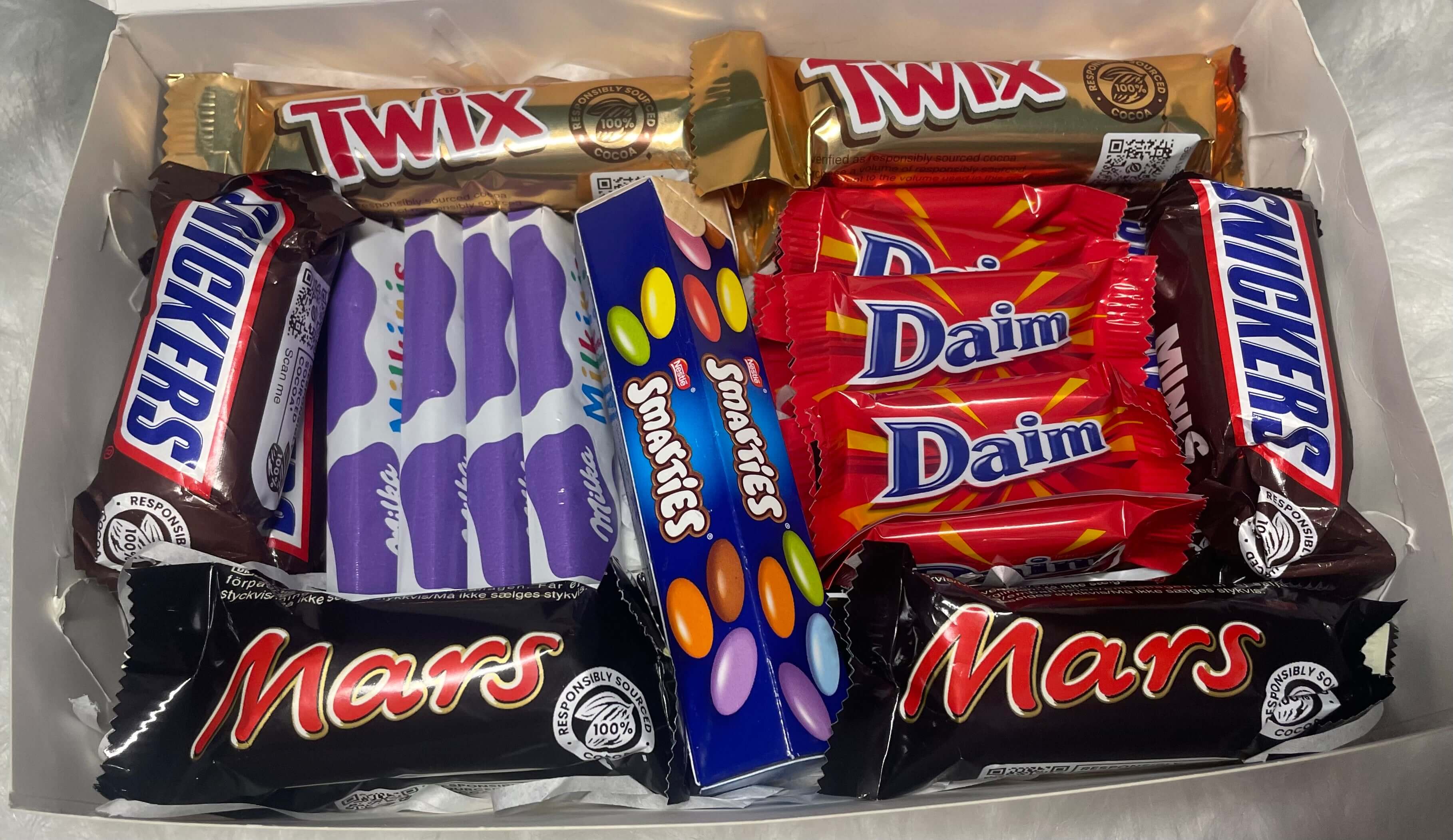 Coffret cadeau contenant un assortiment de chocolats : Twix, Mars, Milka, Snickers, Daim et Smarties.