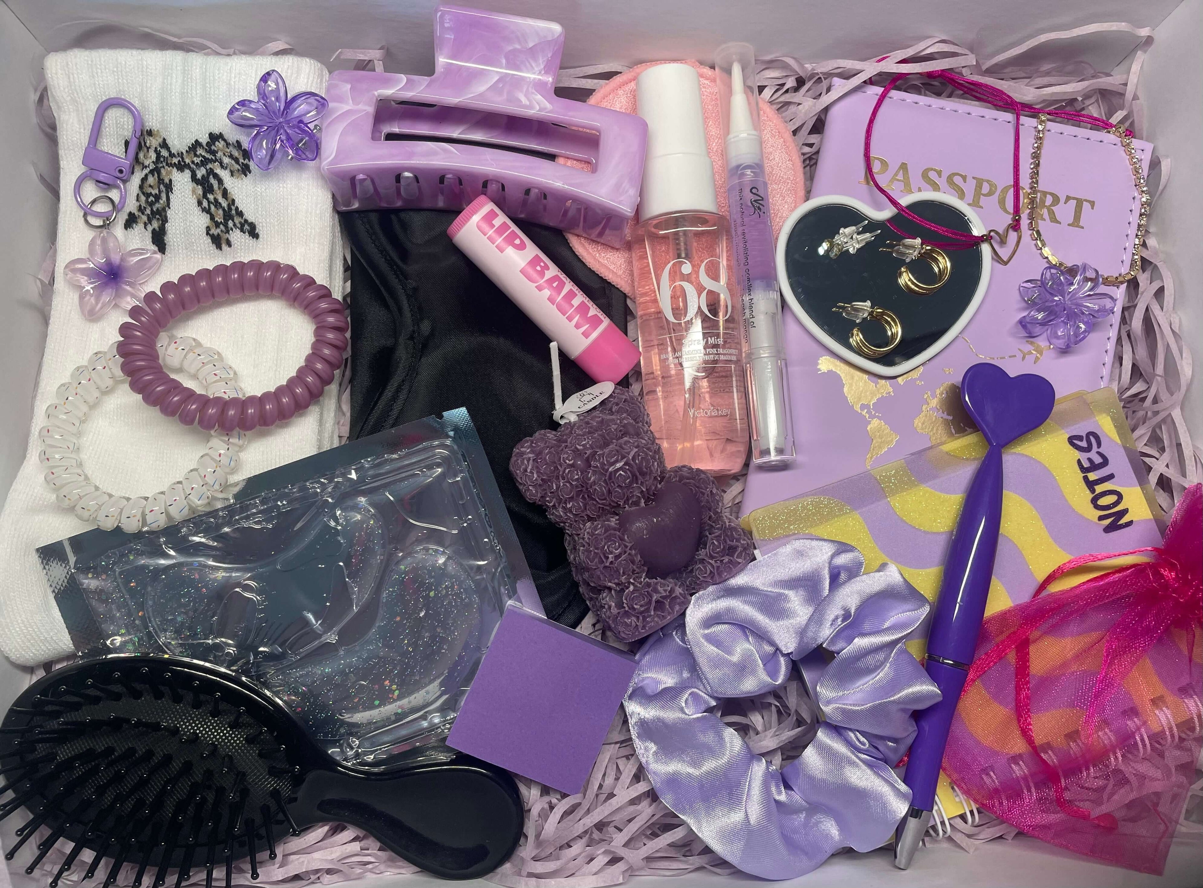 Coffret cadeau sur le thème violet, contenant de nombreux accessoires : porte passeport, pince à cheveux, brosse, baume à lèvres, carnet, bijoux et beaucoup d'autres.