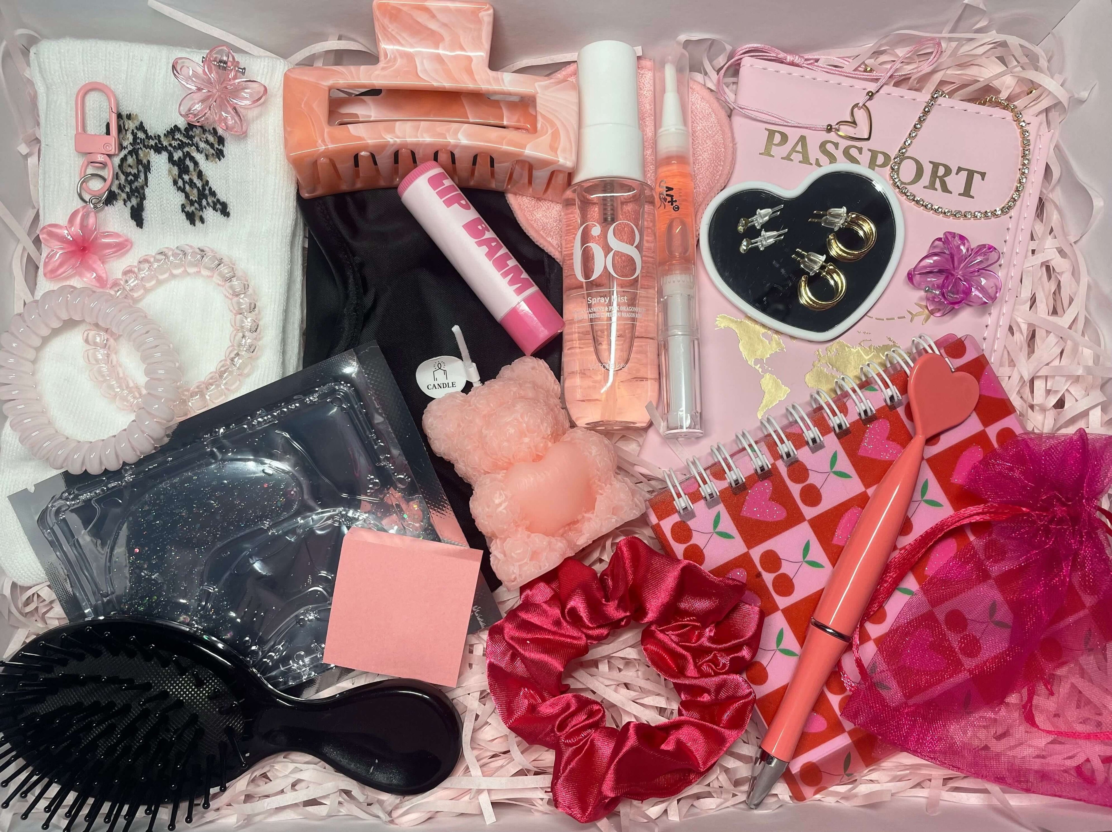 Coffret cadeau sur le thème rose, contenant de nombreux accessoires : porte passeport, pince à cheveux, brosse, baume à lèvres, carnet, bijoux et beaucoup d'autres.
